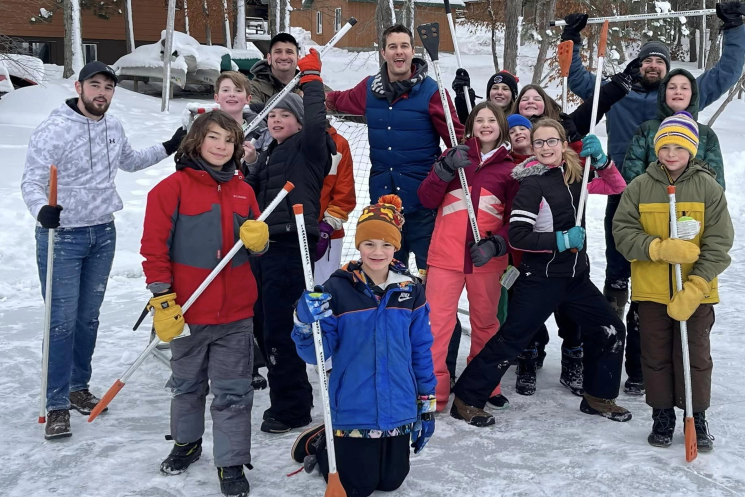 A group of people are standing in the snow holding snow shovels.