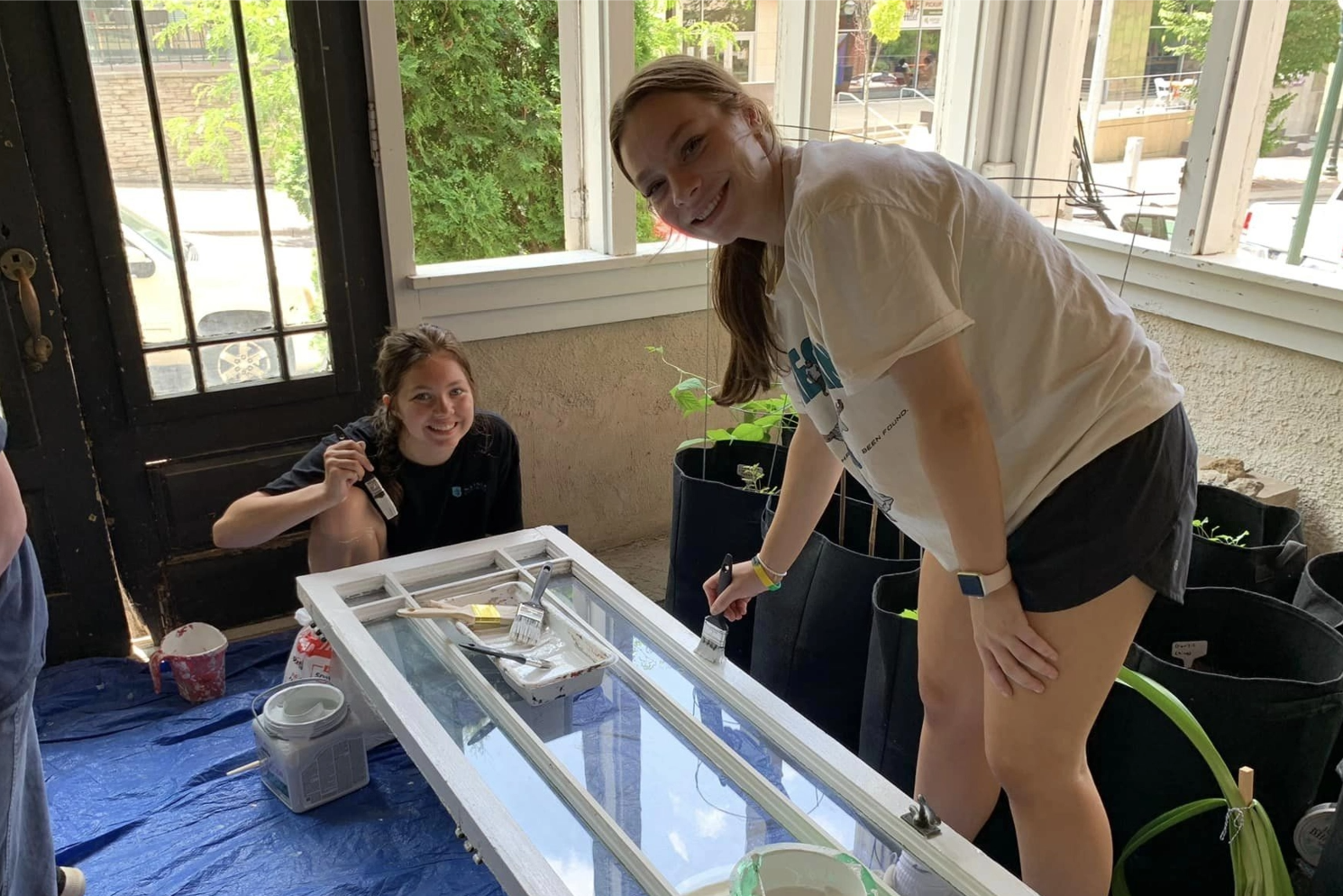 A woman is painting a window frame in a room.