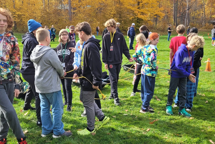 A group of children are standing in a field holding sticks.