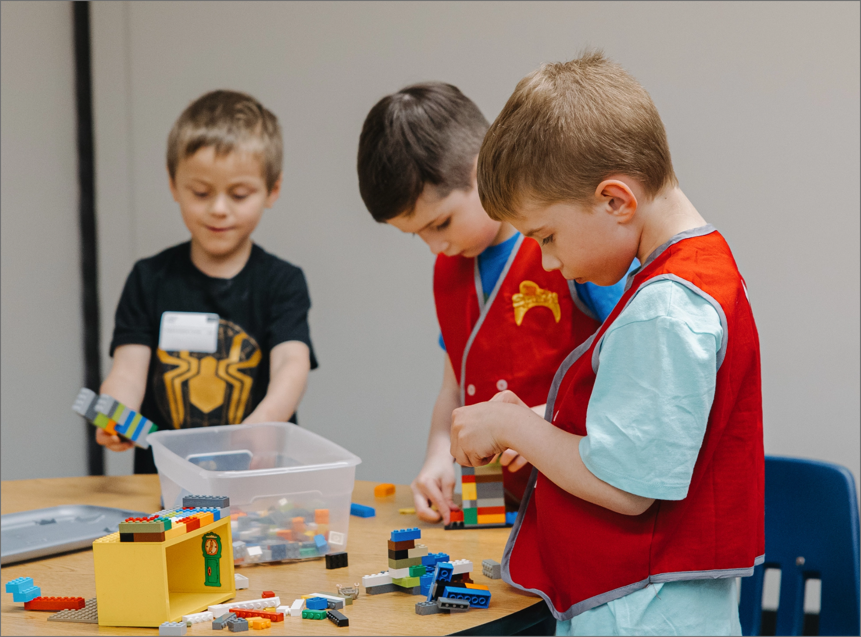 Three young boys are playing with lego blocks at a table.