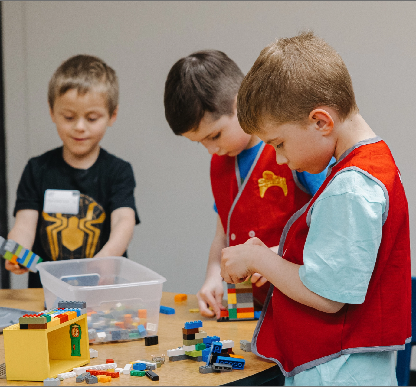 Three young boys are playing with lego blocks at a table