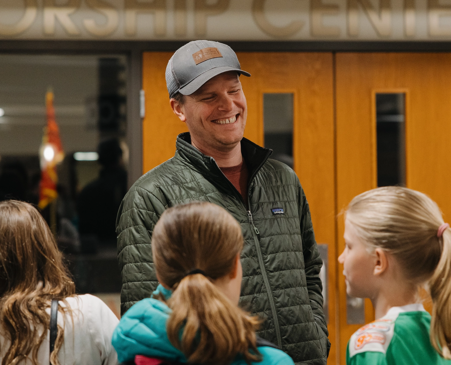 A man in a hat is talking to a group of young girls.
