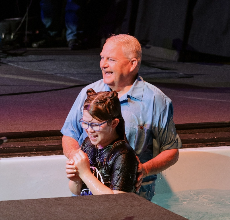 A man and a girl are standing in a bathtub.