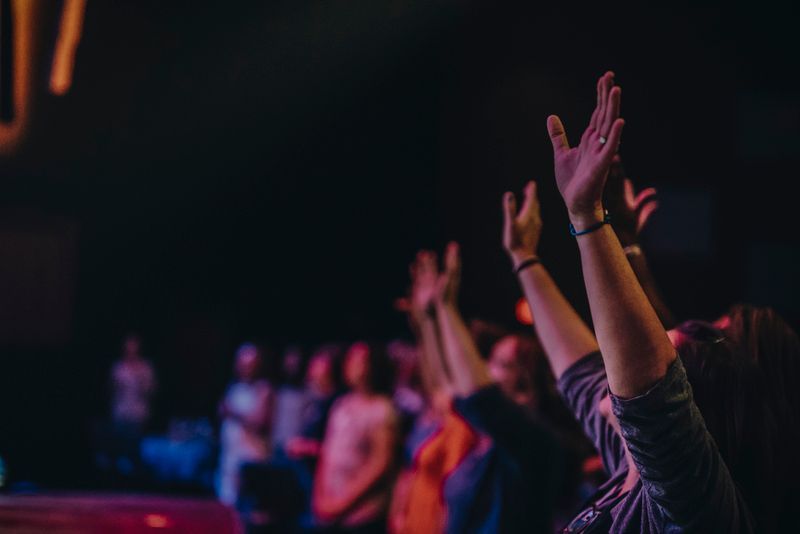 A group of people are raising their hands in the air at a concert.
