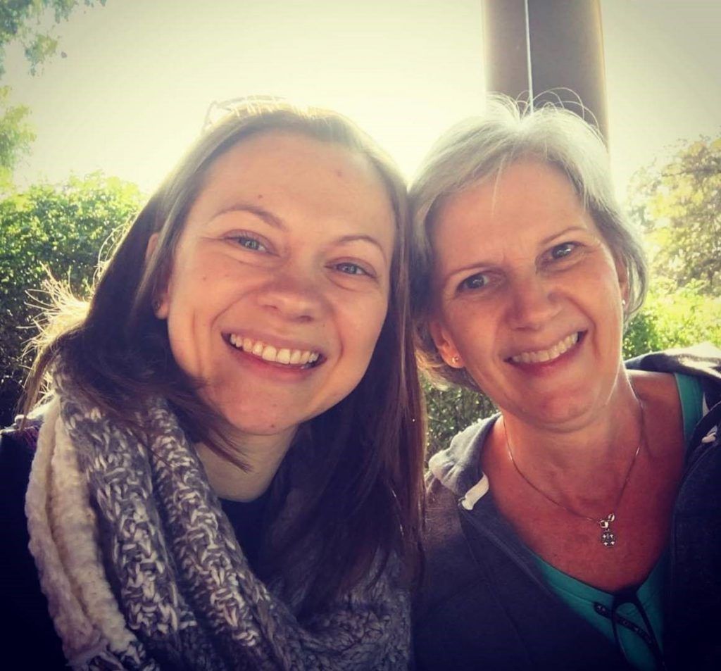 Two women are posing for a picture and smiling for the camera