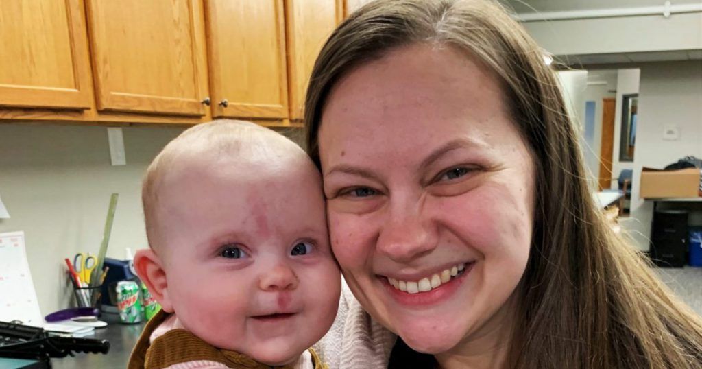 A woman is holding a baby in her arms and smiling.