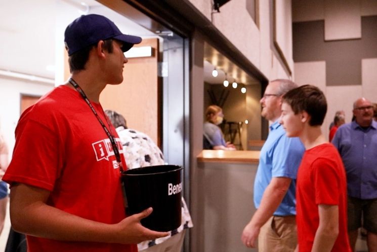 A man in a red shirt is holding a black bucket that says ben