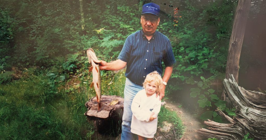 A man and a little girl are standing next to each other holding a fish.