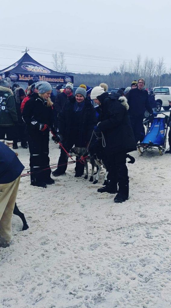 A group of people are standing in the snow talking to each other.