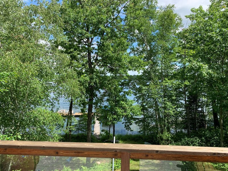 A view of a lake from a deck with trees in the background.