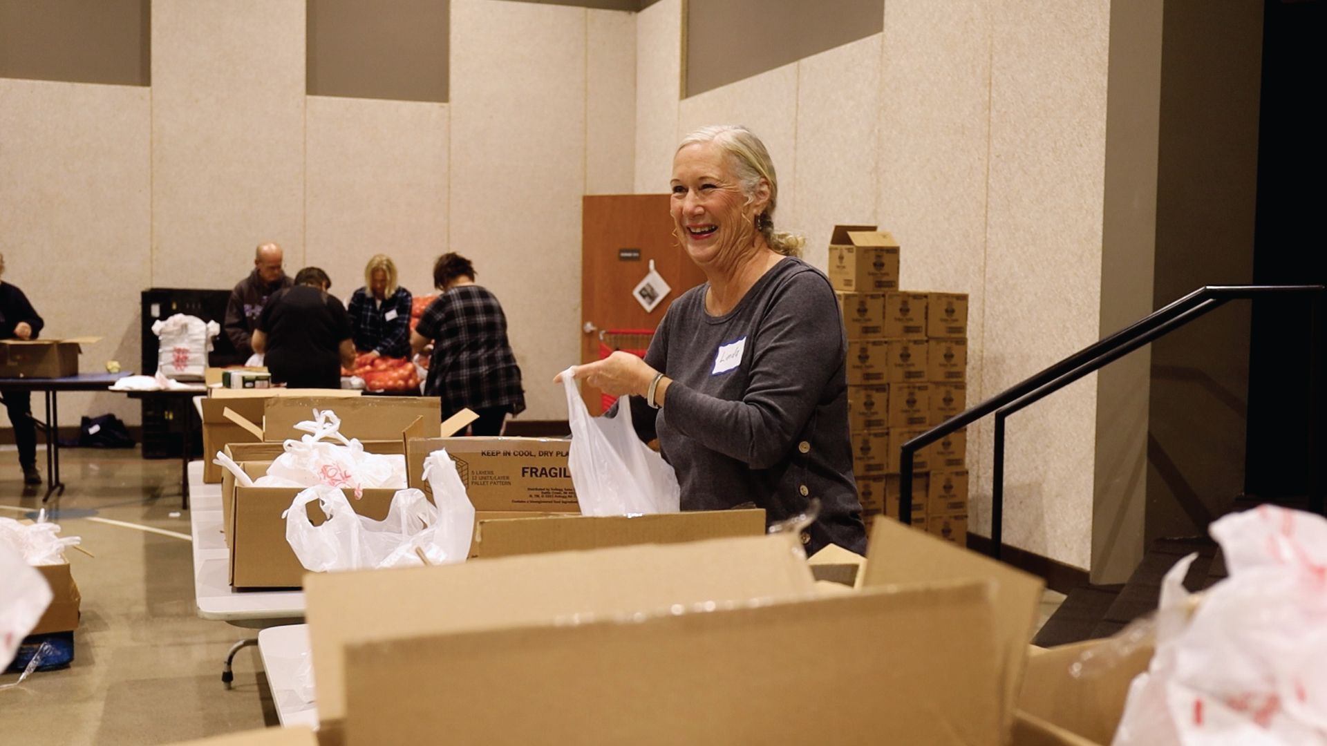 A woman is standing in a room filled with boxes and bags.