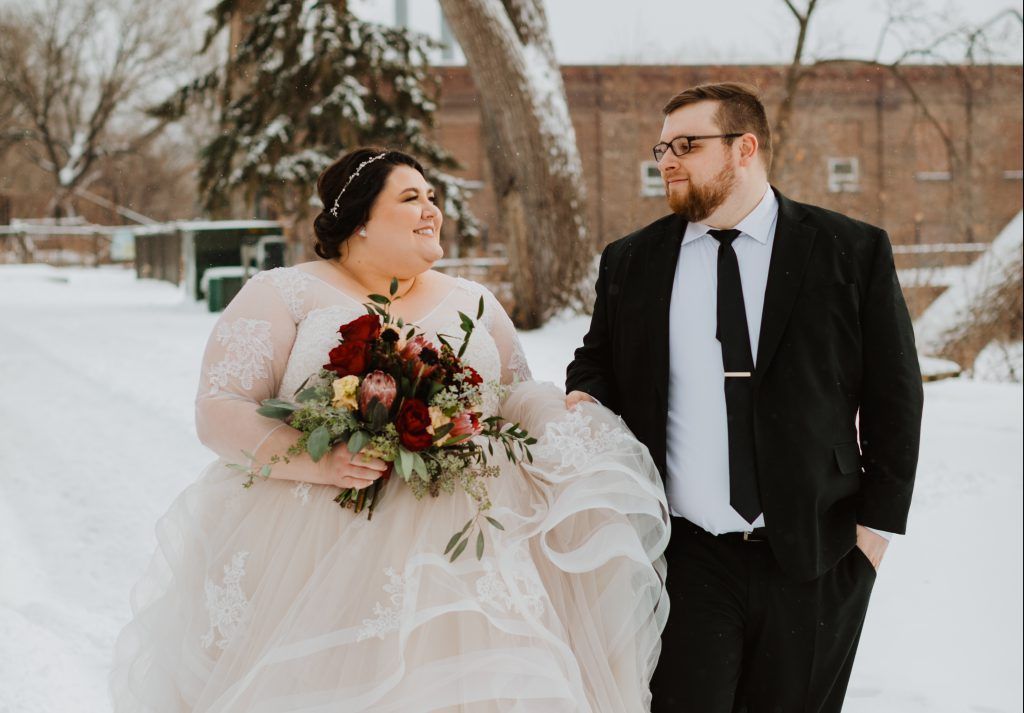 A bride and groom are walking in the snow.