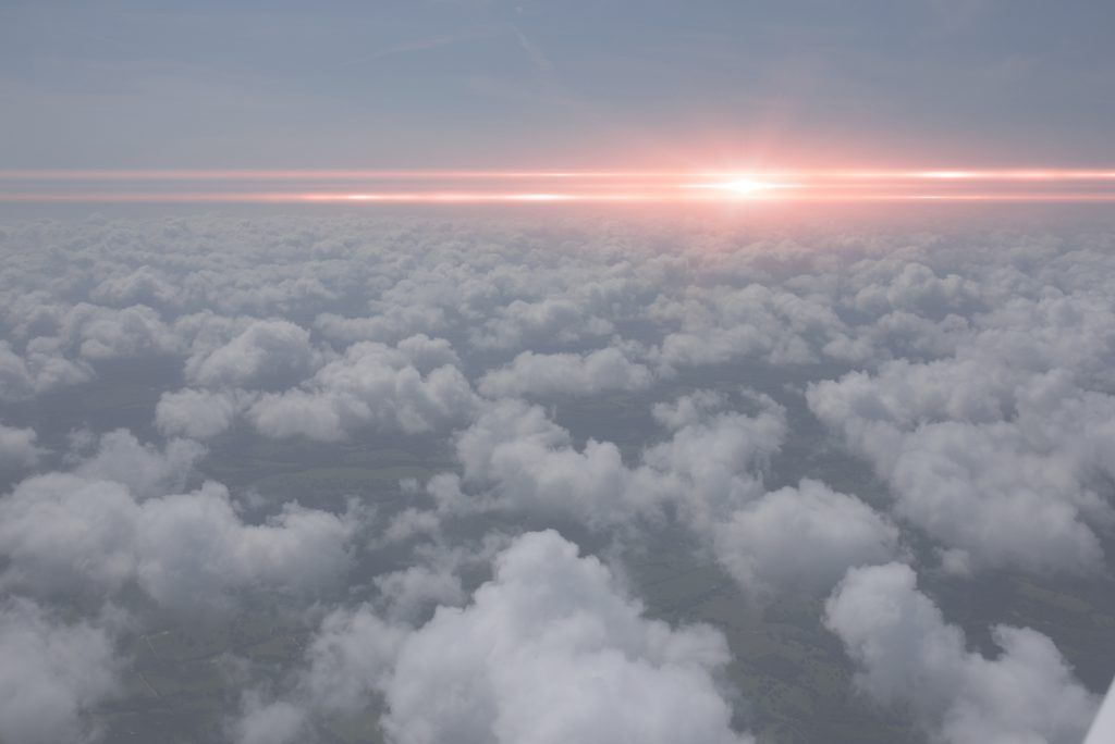 The sun is shining through the clouds in the sky.