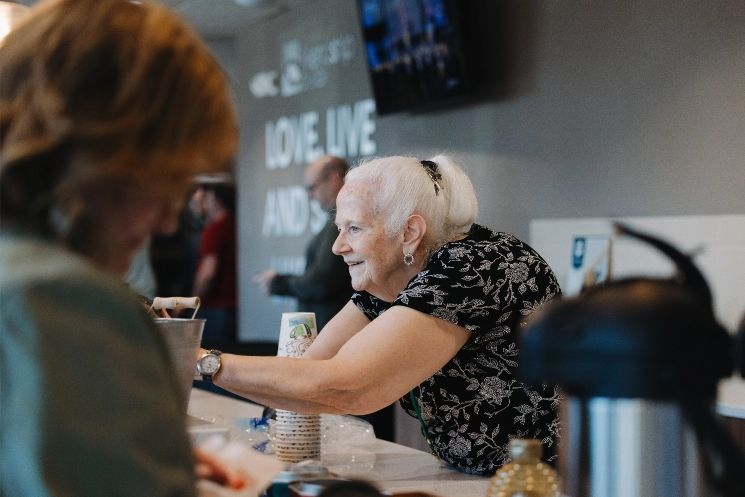 A woman is sitting at a table talking to another woman.