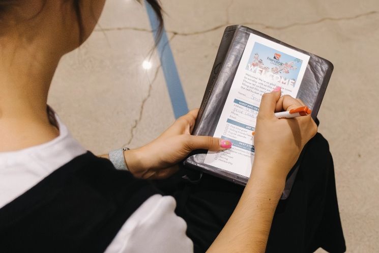 A woman is writing on a piece of paper with a pen.