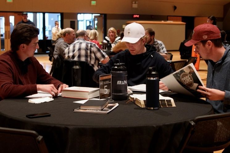 A group of people are sitting around a table reading books
