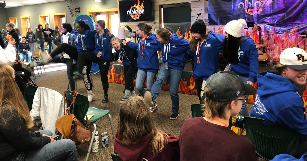 A group of people are dancing in a room in front of a crowd.