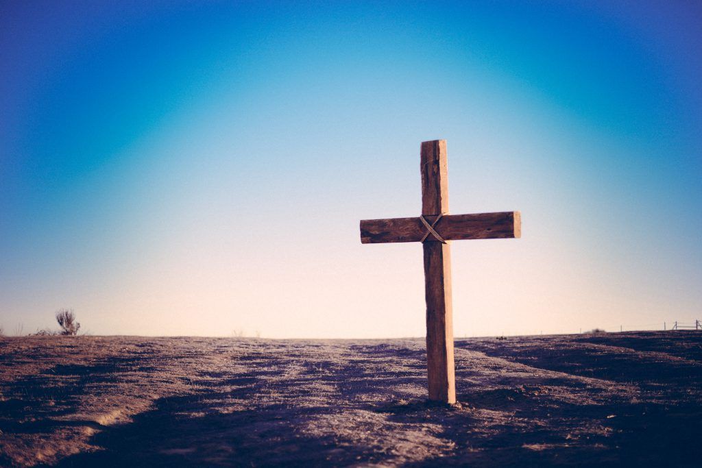 A wooden cross is sitting on top of a dirt hill.