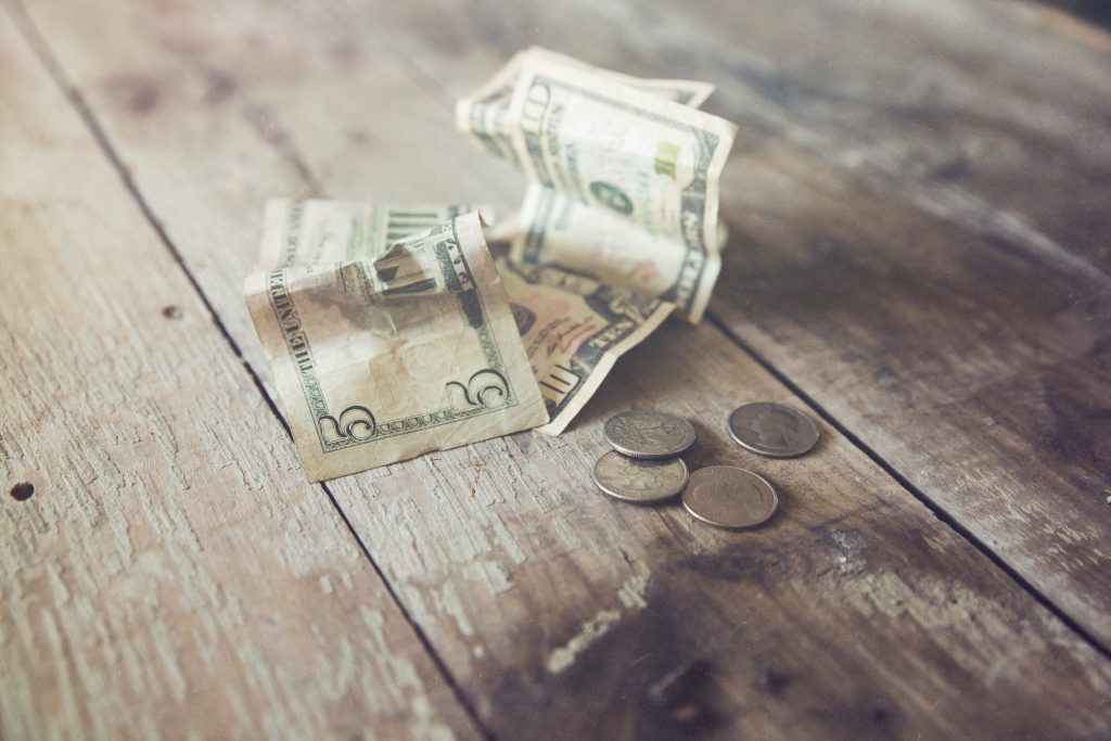 A pile of money and coins on a wooden table.