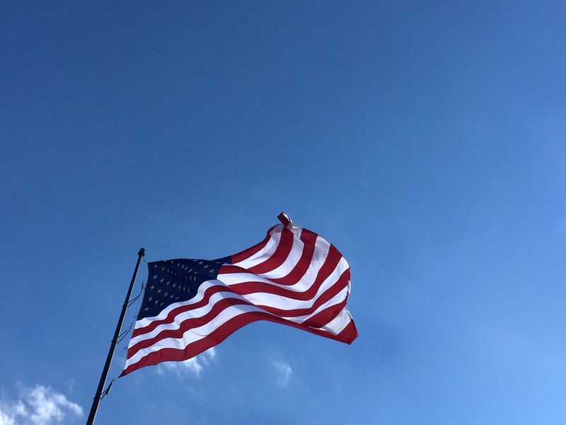 An american flag is waving in the wind against a blue sky