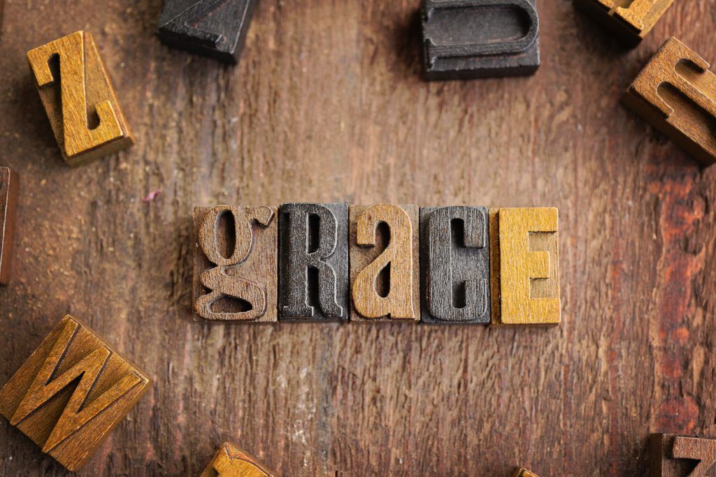 The word grace is written in wooden letterpress type on a wooden surface.