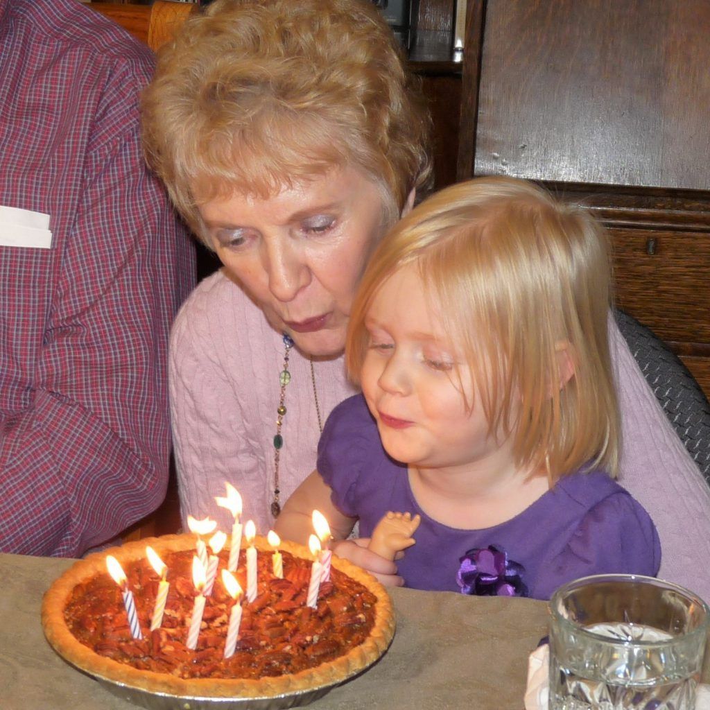 A little girl blowing out candles on a pie