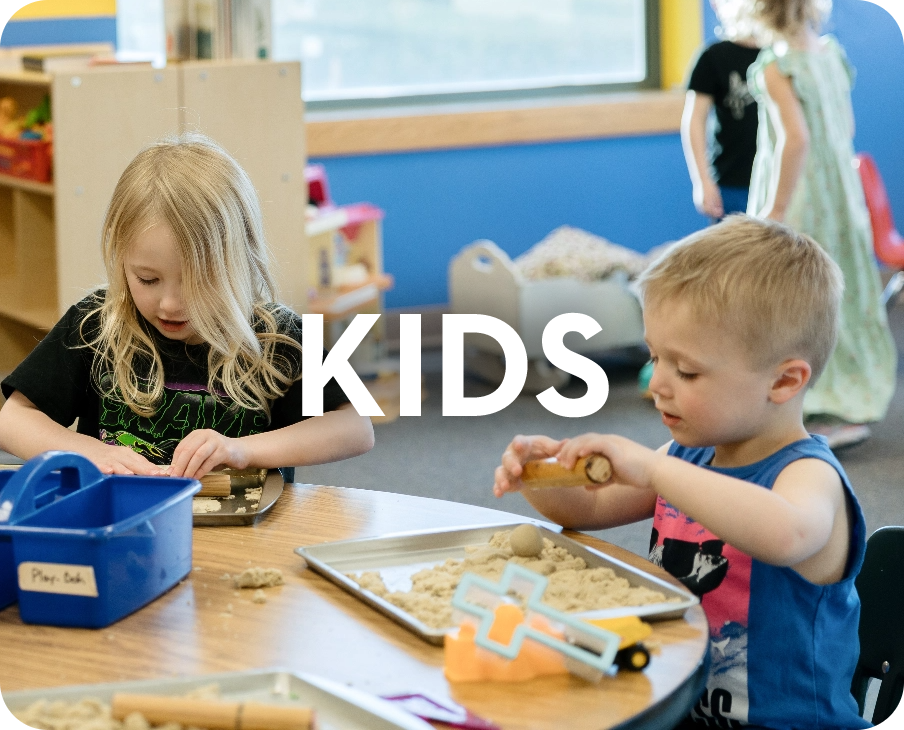 A boy and a girl are sitting at a table playing with dough.