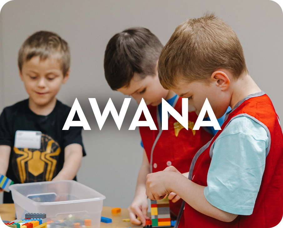 Three young boys are playing with lego blocks and the word awana is above them