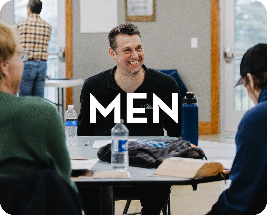 A group of people are sitting around a table with the word men on it.