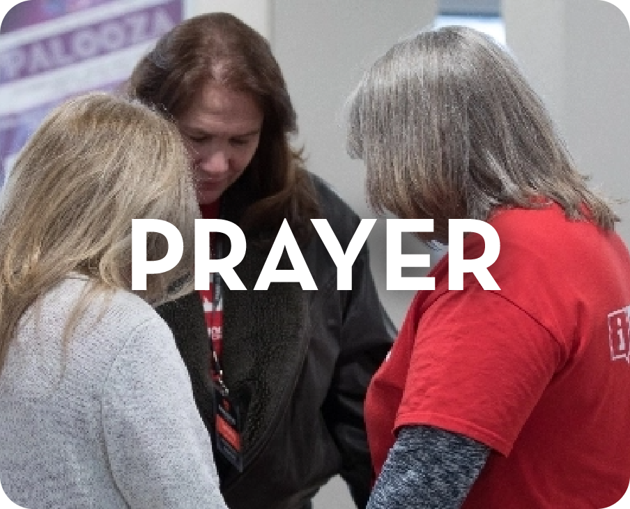 A group of women are praying together with the word prayer above them