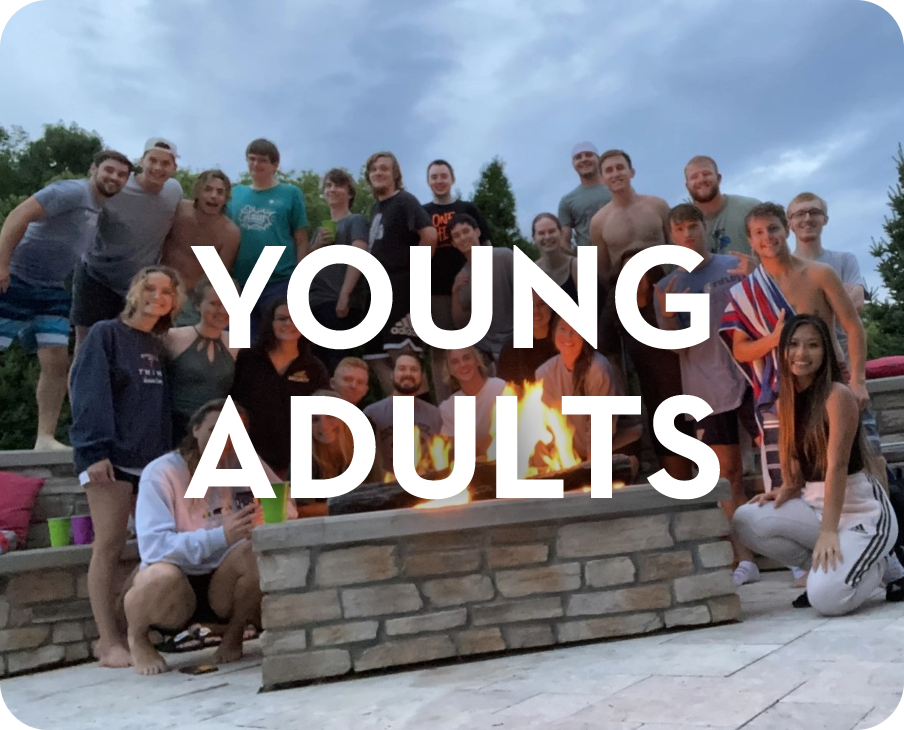 A group of young adults are posing for a picture in front of a fire pit.