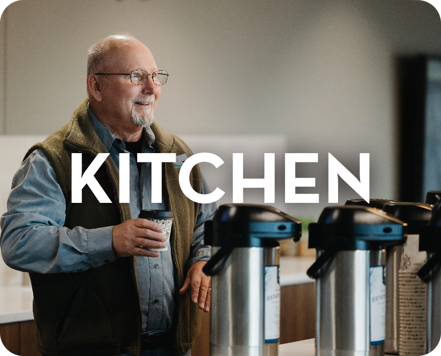 A man is standing in a kitchen holding a cup of coffee.