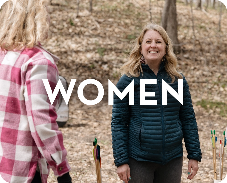 Two women are standing next to each other in the woods.