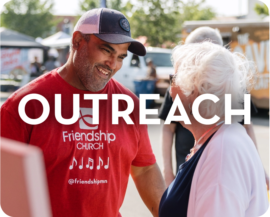 A man in a red shirt is shaking hands with an older woman.