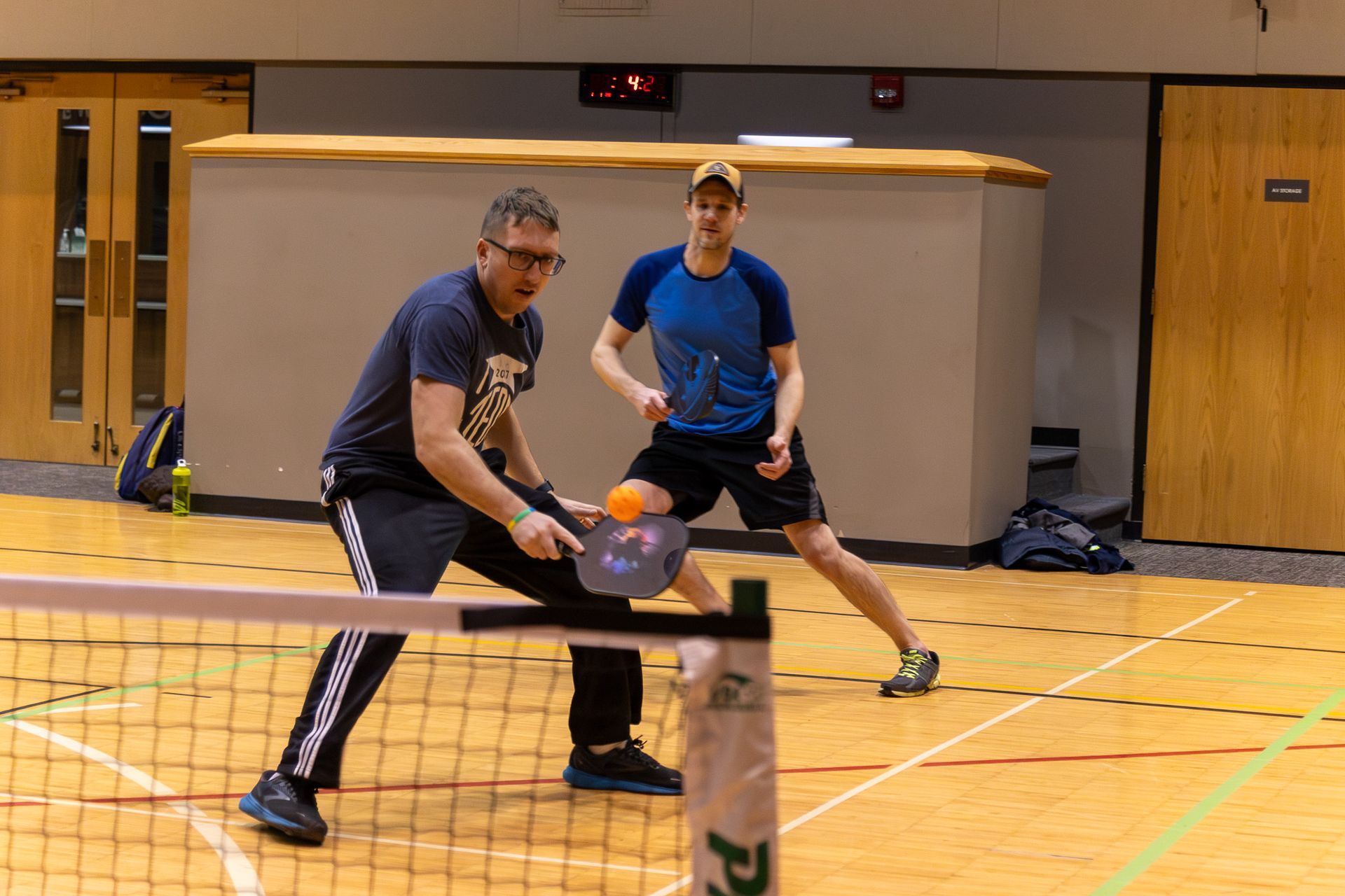 Two men are playing a game of pickleball on a court.