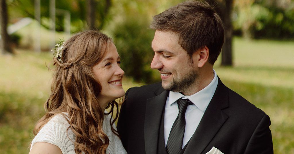 A bride and groom are looking at each other in a park.