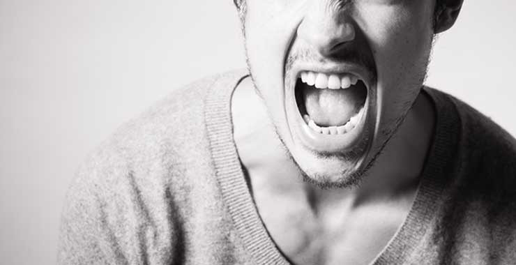 A man is screaming with his mouth open in a black and white photo.