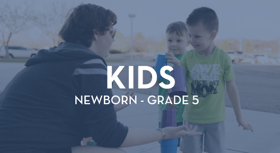 A man is talking to two young boys in a parking lot.