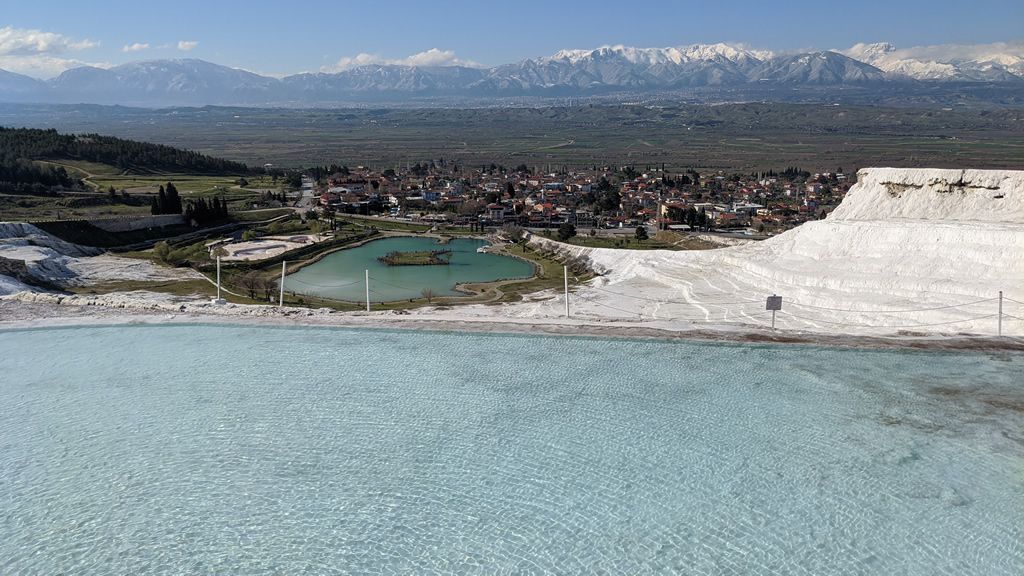 A large body of water with mountains in the background and a city in the distance.