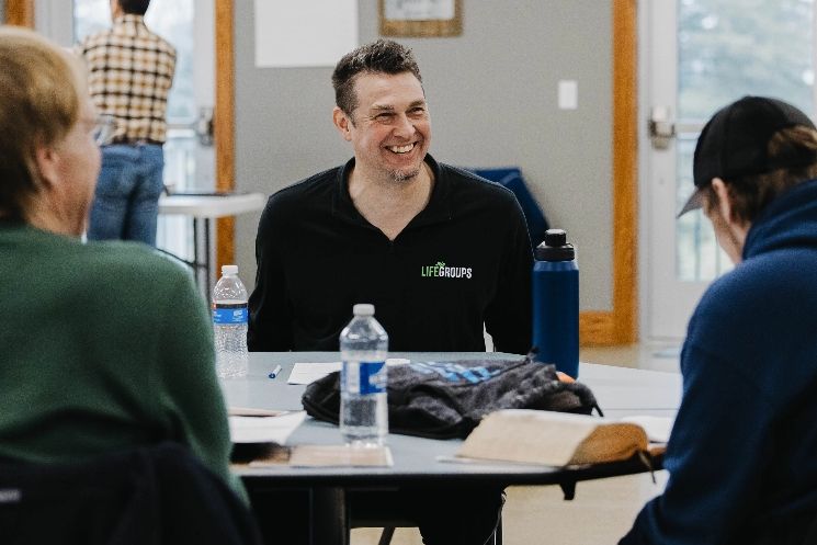 A man is sitting at a table talking to a group of people.