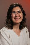 A woman wearing glasses and a white shirt is smiling for the camera.