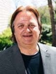 A man in a suit and black shirt is smiling for the camera.