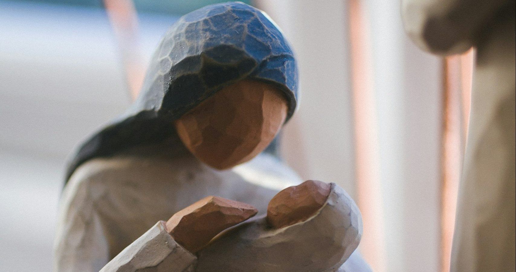 A wooden statue of a woman holding a baby in her arms.