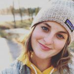 A close up of a woman wearing a beanie and smiling.