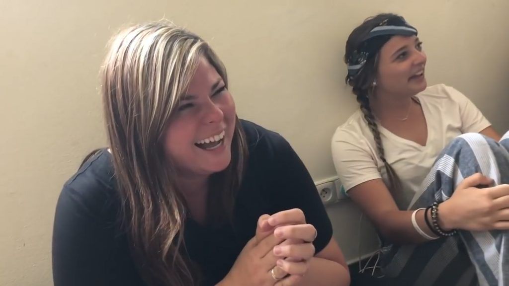 Two young women are sitting next to each other and laughing.
