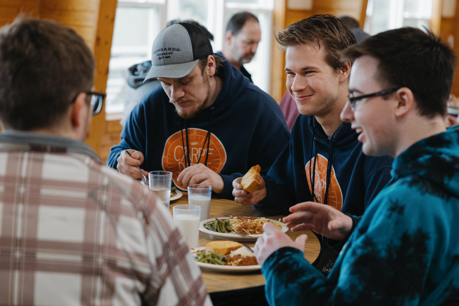 A group of young men are sitting at a table eating food.