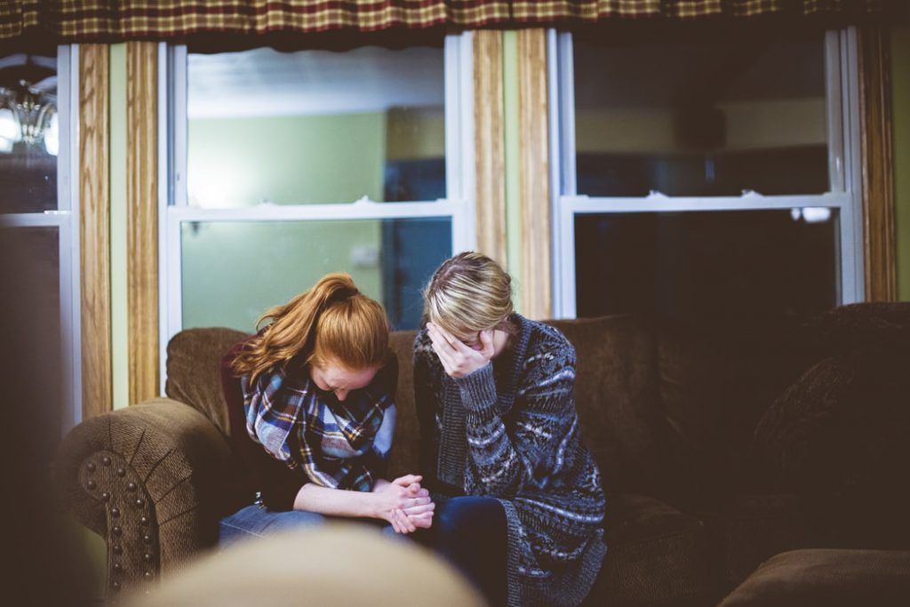 A man and a woman are sitting on a couch in a living room.
