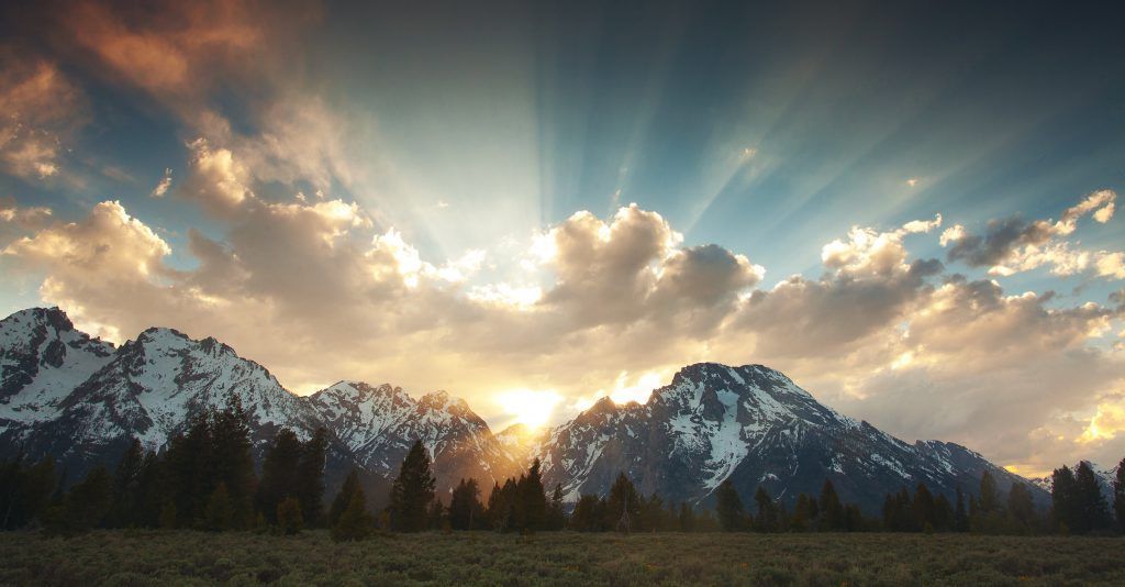 The sun is shining through the clouds over the mountains