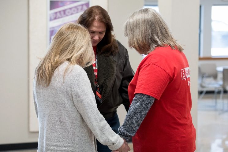 A group of people are holding hands in a room.