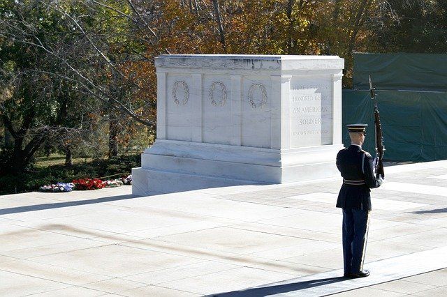 A man in a military uniform stands in front of a grave